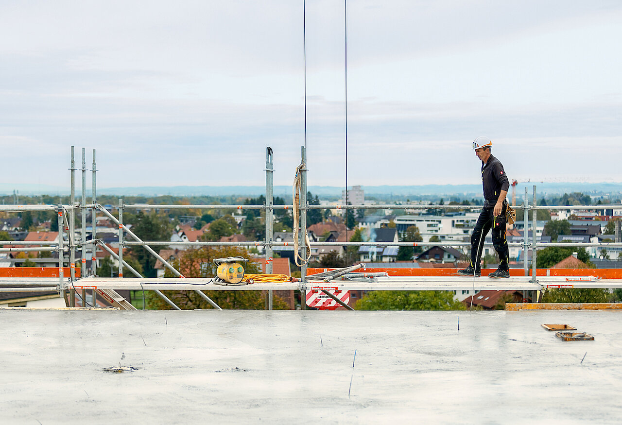 Jäger Bau Mitarbeiter läuft auf der Baustelle auf dem Gerüst entlang